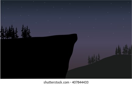 silhouette of cliff at night scenery with fir trees