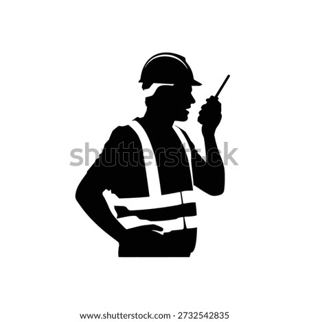 Silhouette of a construction worker communicating with a handheld radio