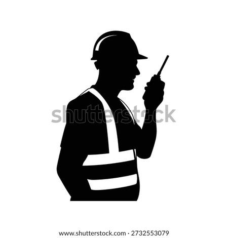 Silhouette of a construction worker communicating with a handheld radio