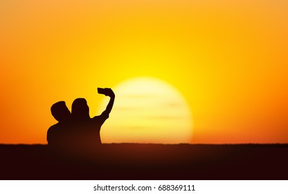 Silhouette couple man and woman take selfie together under sunset sky background