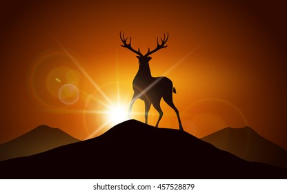 Silhouette of deer on a mountain peak against sunset landscape.