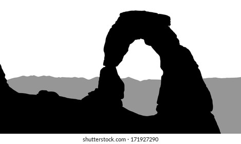 Silhouette of Delicate Arch with mountains in the background