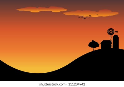 Silhouette of a farm house on top of a hill in the sunset. Or sunrise.