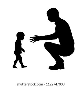 Silhouette of father and child. The child takes the first steps in his life and his father watches him.