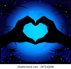 Silhouette of hands making a heart on a background of the night sky and the moon.