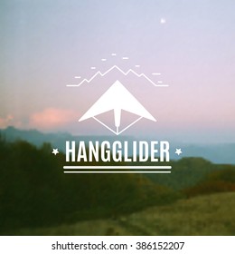 Silhouette of a hangglider with a paddle on a postcard with a photo blurred.Vintage hangglider logo, labels and badges