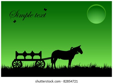 Silhouette of a horse with a wagon standing in a meadow under the full moon