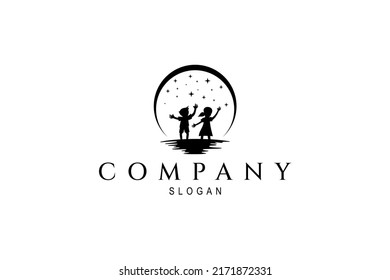 silhouette logo of boy and girl playing under the stars at night decorated with full moon
