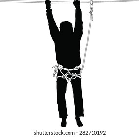 Silhouette of a man hanging on a highline in a safety harness, trying to get back on the rope