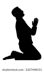 Silhouette of a man sitting on her knees praying. Side view