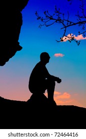 Silhouette of a man sitting at sunset skyline