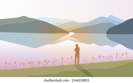 Silhouette of a man stand alone on grass fields front of mountains landscpae and lake 