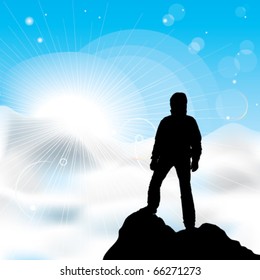 A silhouette of man staying on a top of a mountain and sun rays