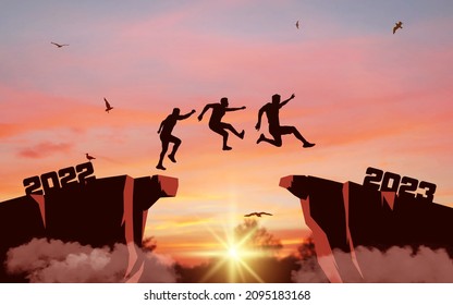 Silhouette of men jumping from a cliff over a cliff with sunlight. Sunset sky with clouds and flying birds. Leap concept in 2023.