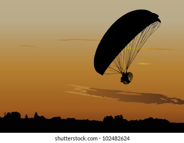 Silhouette of powered paraglide or paramotor against sunset sky