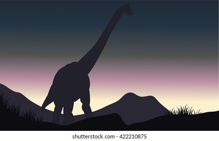 Silhouette of single brachiosaurus in hills at the morning