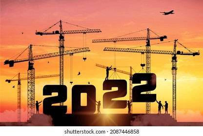 Silhouette staff works as a to prepare to welcome the new year 2022. Large construction site, many construction cranes set numbers 2022. Construction team sets numbers for New Year 2022. Vector.