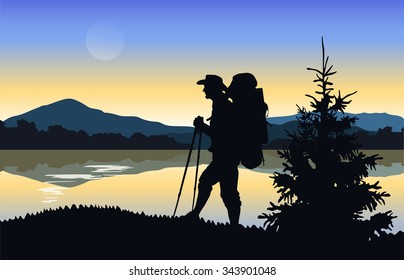 Silhouette of a tourist on a background of mountains and water. Mountain landscape at dawn. 