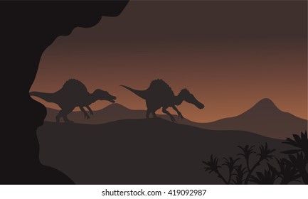 Silhouette of two spinosaurus walking in hills at night