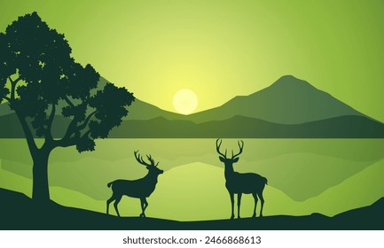 Silhouette of wild deer with trees on the edge of the lake and beautiful mountains in the morning,evening, sunset,sunrise