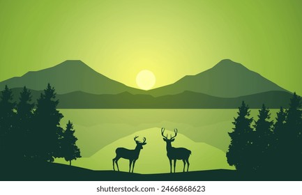 Silhouette of wild deer with trees on the edge of the lake and beautiful mountains in the morning,evening, sunset,sunrise
