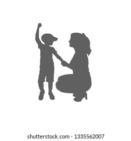 The silhouette of a woman crouched and standing child. Mom holds her son's hand. The boy raised one hand.