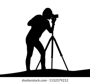 Silhouette of woman photographer shooting landscape with camera on tripod