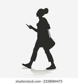 Silhouette of a woman walking while holding a cell phone