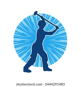 Silhouette of a worker in action pose using his sledge hammer tool.