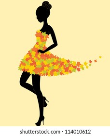 Silhouette of the young beautiful dancer girl in dress of autumn leaves