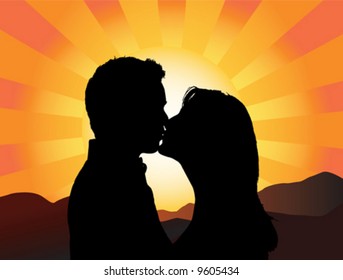 Silhouette of a young couple kissing with the sun setting behind them