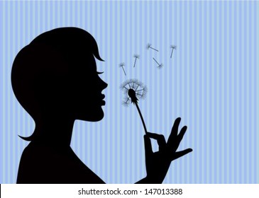 silhouette of a young girl holding a dandelion and blowing on it.