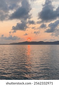 Silhouetted mountains at dusk, reflected in the tranquil waters below a vibrant sunset sky