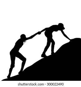 Silhouettes of girl giving helping hand to her friend to climb up the last section of mountain