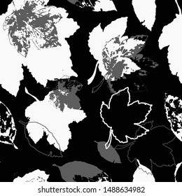Silhouettes of maple leaves on a black background. Seamless pattern of autumn leaves.
