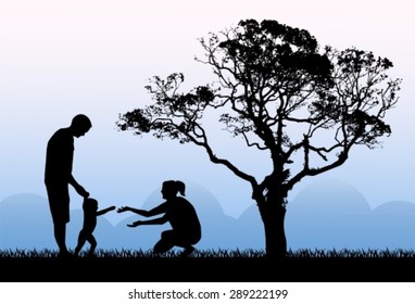 silhouettes of parents with a child playing on the background of the dawn in the morning and a large tree
