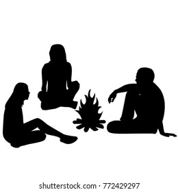 Silhouettes of tourists sitting around a campfire