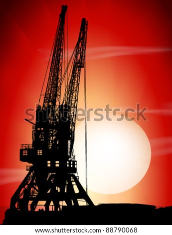 Silhouettes of two port cranes on a sunset