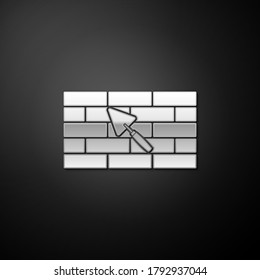 Silver Brick wall with trowel icon isolated on black background. Long shadow style. Vector