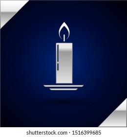 Silver Burning candle in candlestick icon isolated on dark blue background. Old fashioned lit candle. Cylindrical candle stick with burning flame.  Vector Illustration