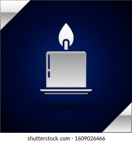 Silver Burning candle in candlestick icon isolated on dark blue background. Cylindrical candle stick with burning flame.  Vector Illustration