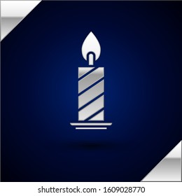 Silver Burning candle in candlestick icon isolated on dark blue background. Cylindrical candle stick with burning flame.  Vector Illustration