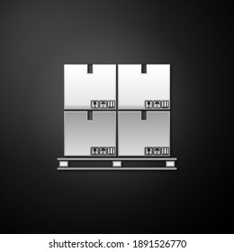 Silver Cardboard boxes on pallet icon isolated on black background. Closed carton delivery packaging box with fragile signs. Long shadow style. Vector.