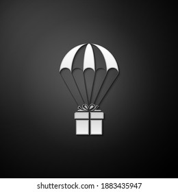 Silver Gift box flying on parachute icon isolated on black background. Delivery service, air shipping concept, bonus concept. Long shadow style. Vector.