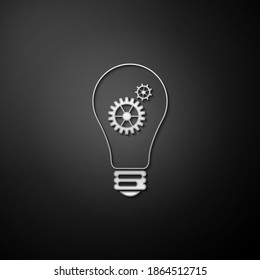 Bombilla de luz plateada y engranaje dentro del icono aislado en el fondo negro. Concepto de innovación. Estilo de sombra larga. Vector.