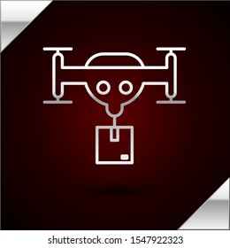 Silver line Delivery drone with the package icon isolated on dark red background. Drone delivering cardboard box.  Vector Illustration