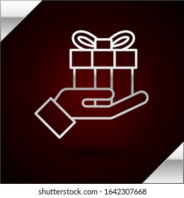 Silver line Gift box in hand icon isolated on dark red background. Merry Christmas and Happy New Year.  Vector Illustration