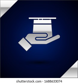 Silver Magician hat in hand icon isolated on dark blue background. Magic trick. Mystery entertainment concept.  Vector Illustration