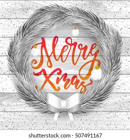 Silver pine branches wreath for Xmas holiday greeting cards. Merry Christmas hand drawn lettering design on white wooden background.