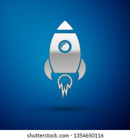 Silver Rocket ship with fire icon isolated on blue background. Space travel. Vector Illustration